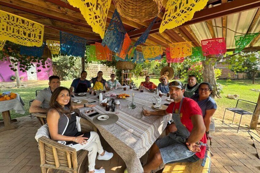 A group of people dining at an outdoor table with colorful paper decorations. 3
