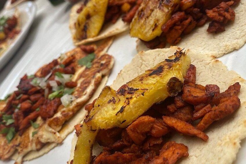 A plate of food with tortillas topped with grilled pineapple and a red meat mixture. 5