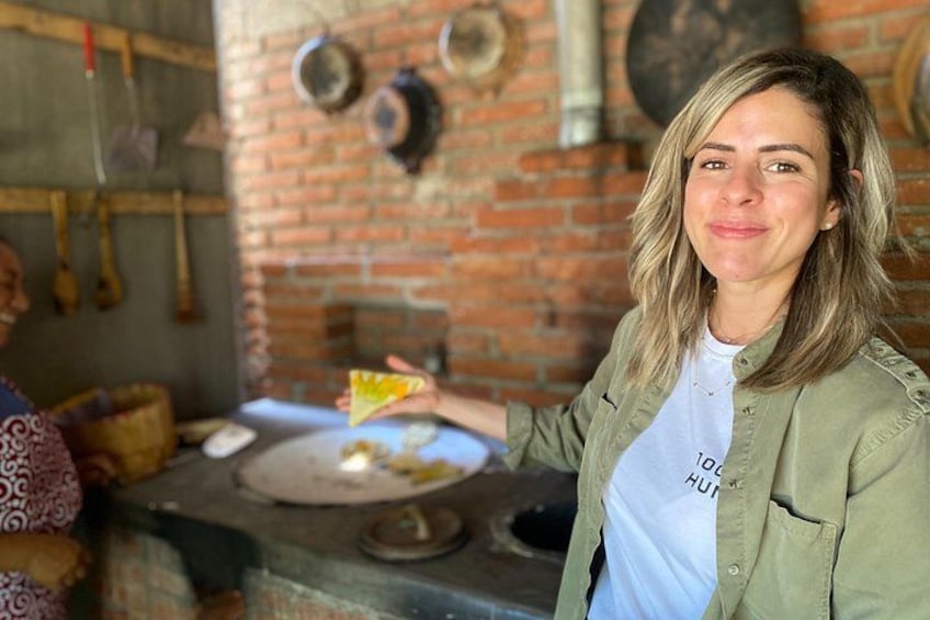A person in a rustic kitchen with brick walls, a brick oven, and hanging utensils. 4