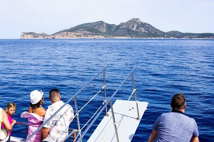 A group of people on a sailboat with a mountainous coastline in the background. 3