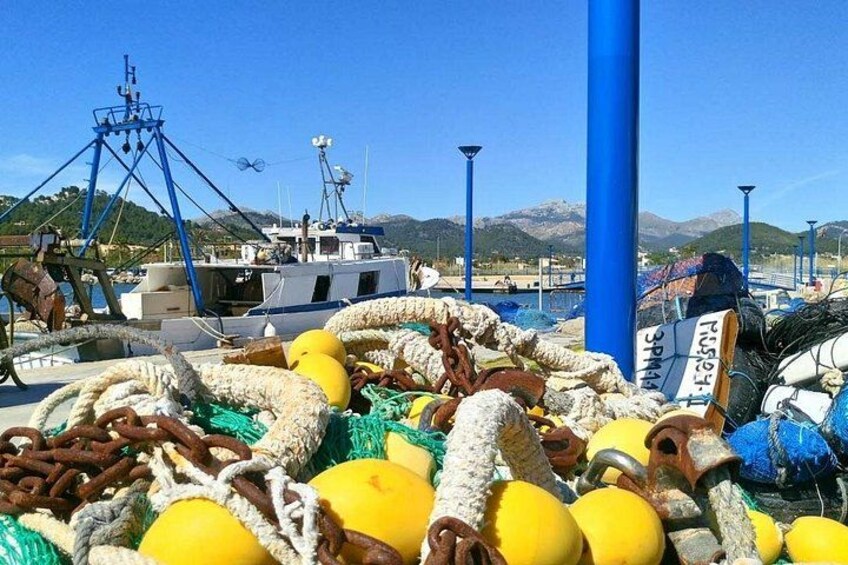 A harbor with fishing equipment, boats, and a mountainous landscape in the background. 5