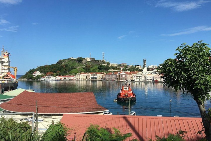 Un porto con un rimorchiatore, edifici e una collina con una torre. 3