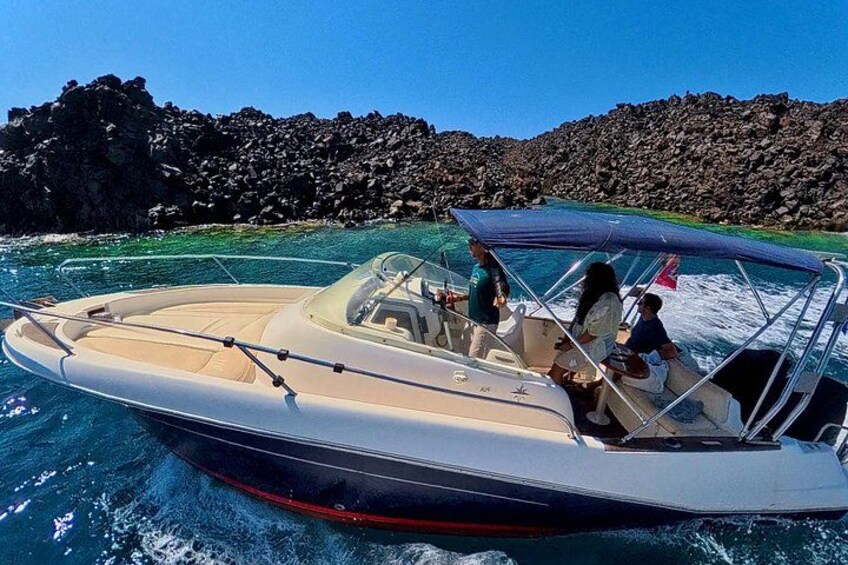 A motorboat on water with rocky coastline in the background. 1