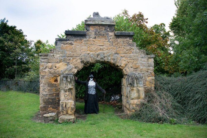 Un arco de piedra con una persona vestida de negro parada frente a él. 4