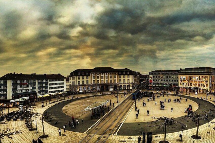 A circular plaza with tram tracks, surrounded by multi-story buildings with commercial establishments. 1
