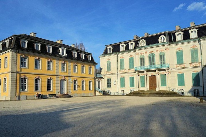 A large yellow building with a balcony and a smaller white building with green shutters. 4