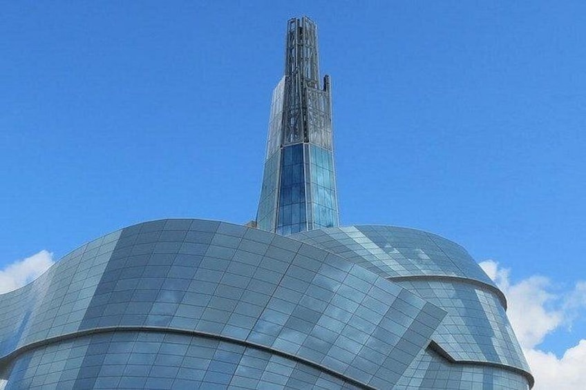 A modern glass skyscraper with a curved facade and a tall, narrow spire. 2