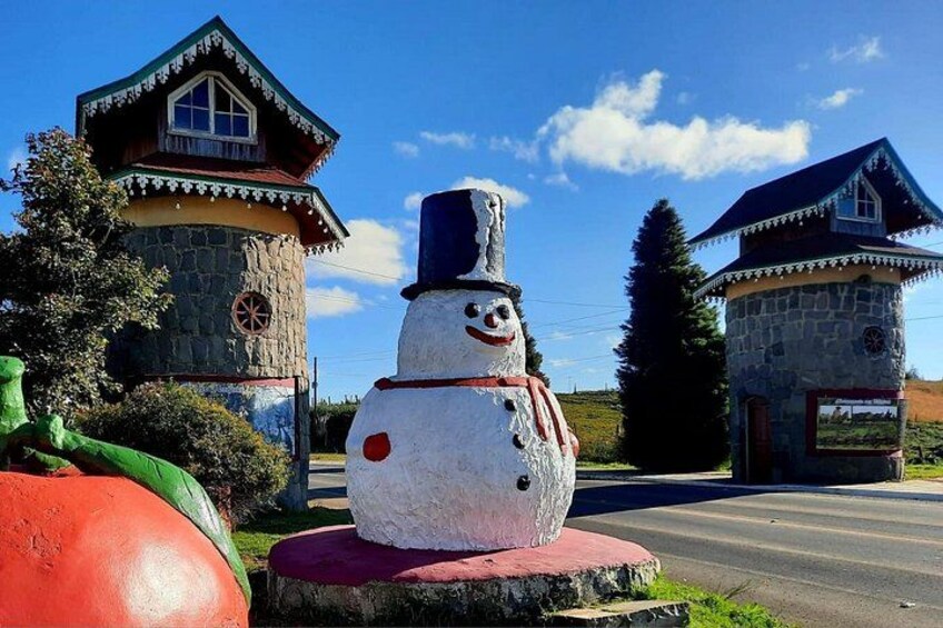 A snowman sculpture, a stone house, and a road. 4