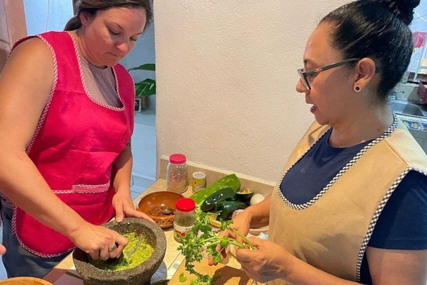 Two people preparing food, one grinding herbs in a mortar. 2