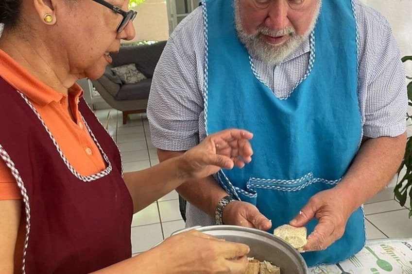 Two people, one wearing a blue apron, preparing food together. 3