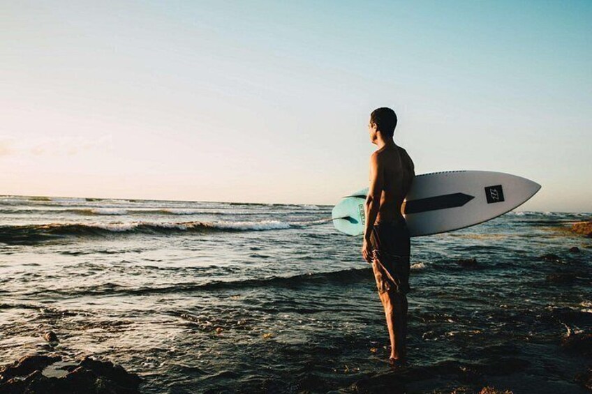 A person holding a surfboard at the beach. 1