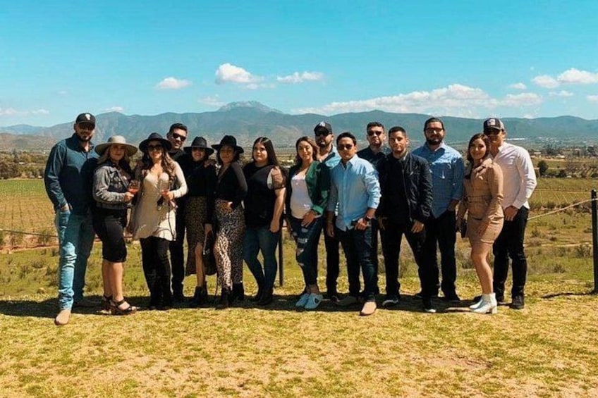Un gruppo di persone in piedi all'aperto, con un paesaggio montuoso sullo sfondo. 5