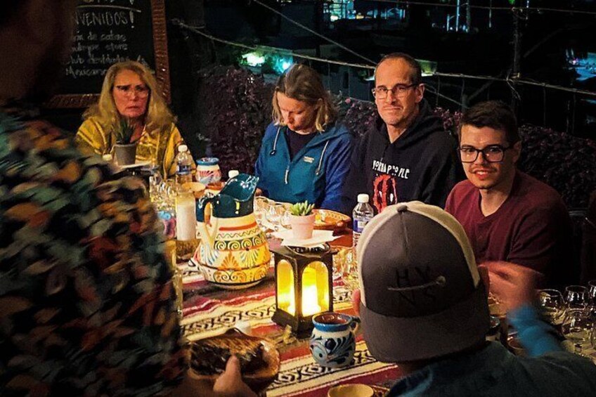 A group of people seated around a table with a cake and various dishes. 3