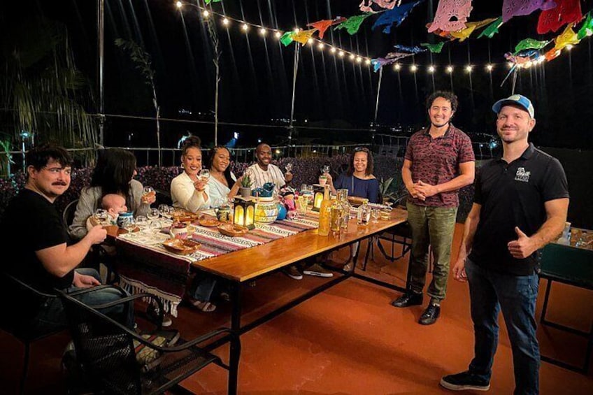 A group of people dining outdoors at night with string lights overhead. 2