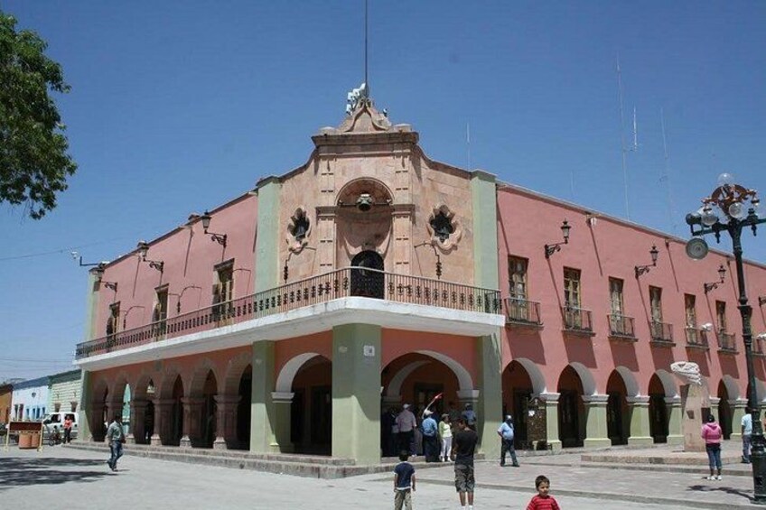 Un bâtiment historique à la façade rose, doté de fenêtres en arc de cercle et d’un balcon. 5