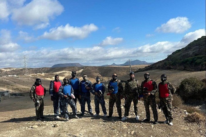 A group of people in military attire standing on a dirt road with a mountainous landscape in the background. 2