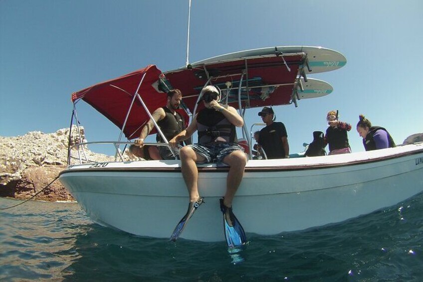 Una barca con passeggeri, una costa rocciosa e acque cristalline blu. 2