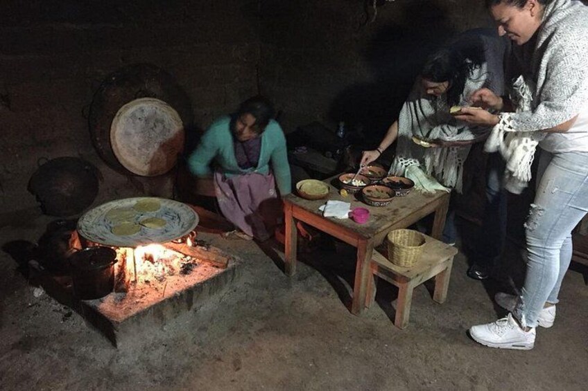 Una escena tradicional de cocina con fuego, utensilios y preparación de alimentos. 5