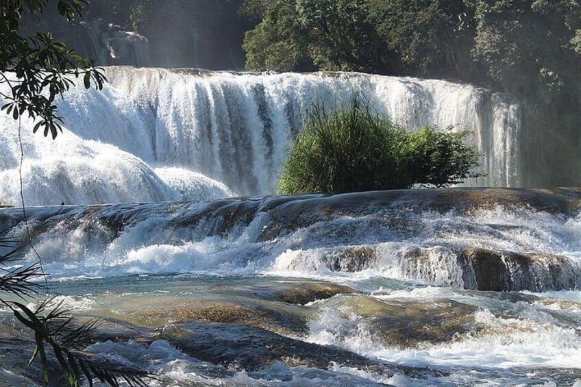 A waterfall cascading over rocks, surrounded by lush greenery. 2