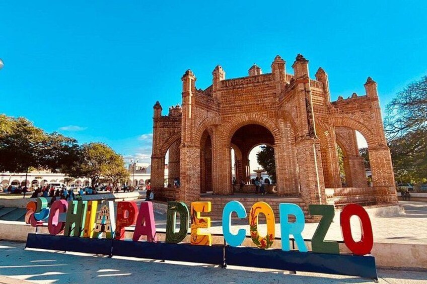 A historic brick archway with colorful letters spelling 'CHAPADA DE CORZO' in the foreground. 1
