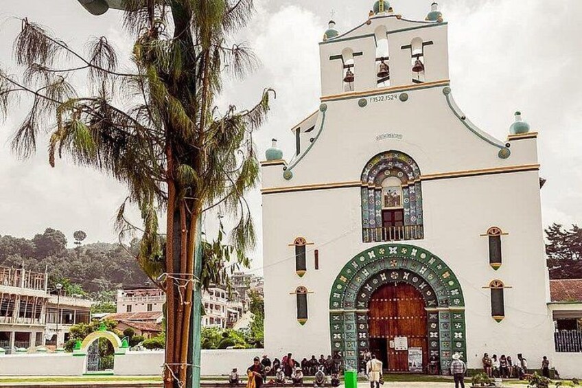 A white church with a large arched entrance and a bell tower. 4