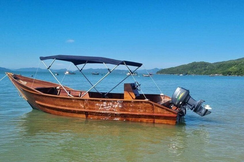Una barca de madera con toldo, flotando en aguas tranquilas bajo un cielo despejado y colinas lejanas. 4