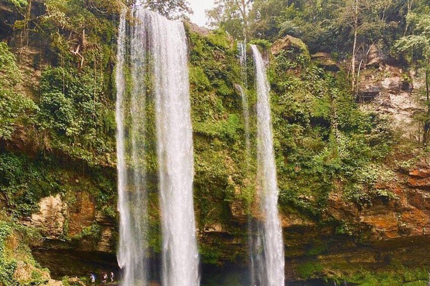 A waterfall with multiple streams cascading down a rocky cliff surrounded by lush greenery. 3