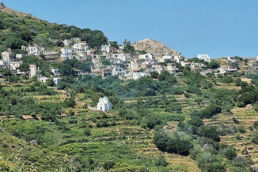 A coastal village with white buildings, green hills, and a rocky hill in the background. 4