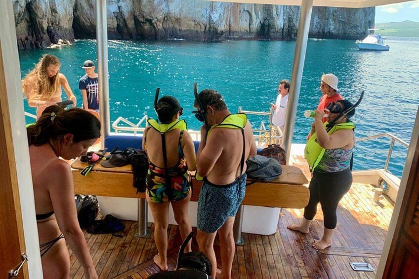 Des personnes à bord d’un bateau se préparent à une activité nautique, avec des falaises rocheuses en arrière-plan. 4