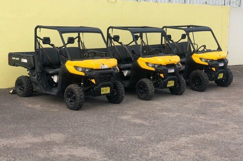 Four yellow golf carts parked against a yellow wall. 5