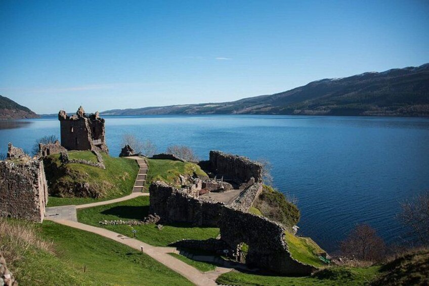 A historic castle ruin by a lake with a clear sky. 1