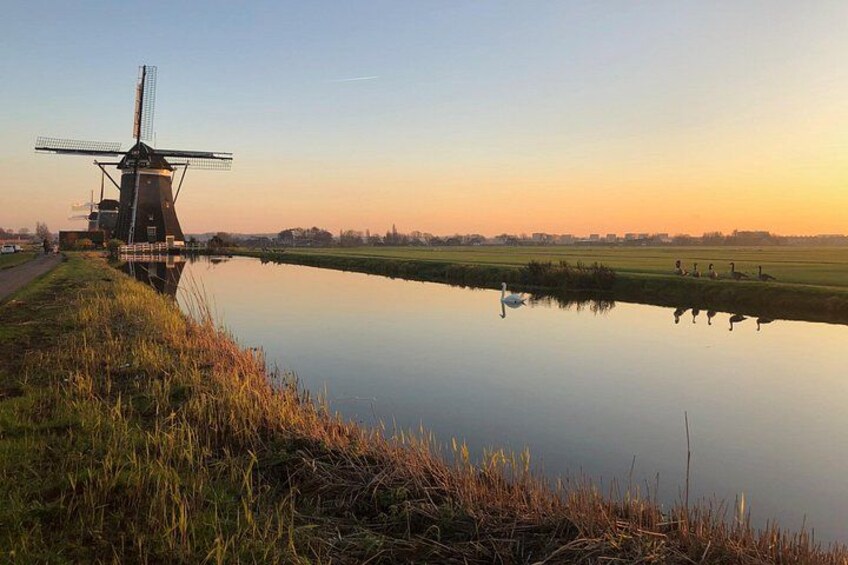 Un moulin à vent au bord d’un plan d’eau paisible, au coucher du soleil. 2