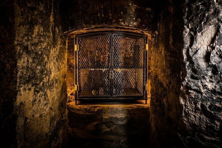 A stone wall with a metal gate in a cave. 2