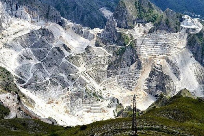 A mountainous landscape with terraced mining areas and a power line structure. 2
