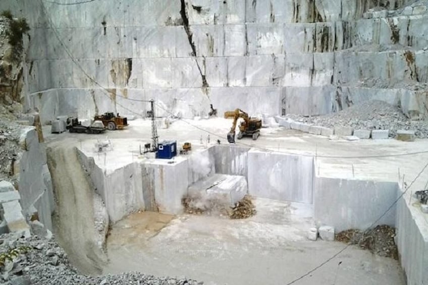 A construction site with a large excavation, heavy machinery, and concrete blocks. 4