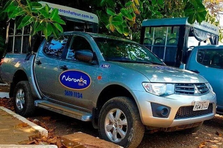A silver pickup truck with 'Noronta Tour' branding parked on a street. 4