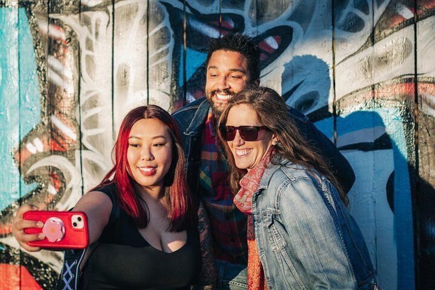 Three people taking a selfie with graffiti in the background. 2
