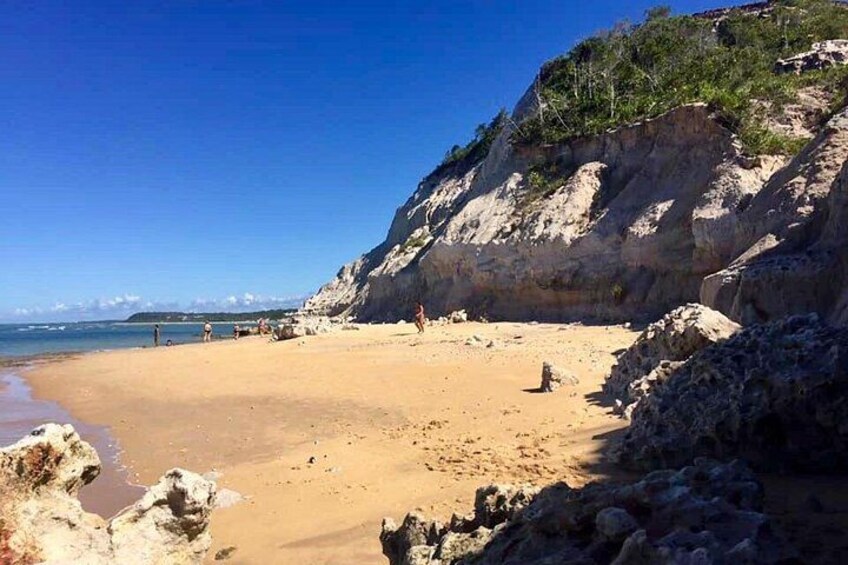 A beach with rocky cliffs and a clear blue sky. 5