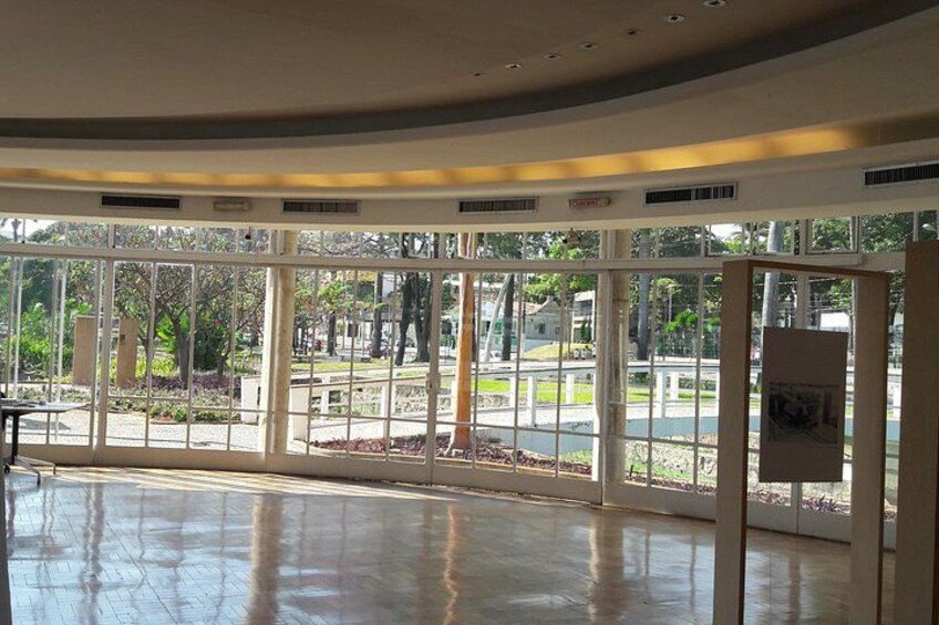 A spacious indoor area with large windows, a polished floor, and a view of an outdoor park. 3