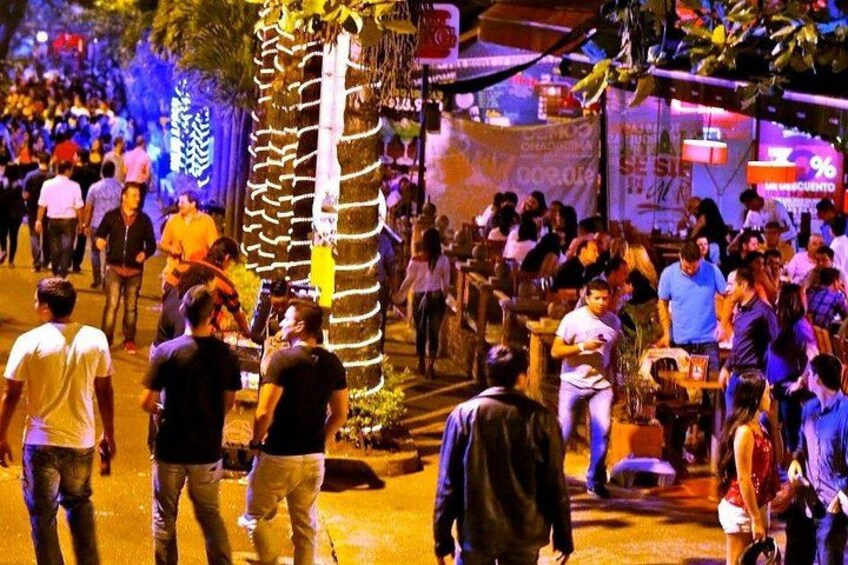 Una calle concurrida de noche, con gente caminando y reunida. 5