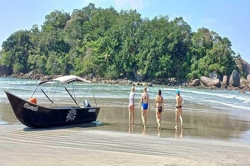 En strand med en båd og folk der går langs kysten. 2