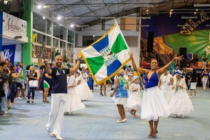 A parade with participants holding a flag, in an indoor venue with a stage and audience. 1