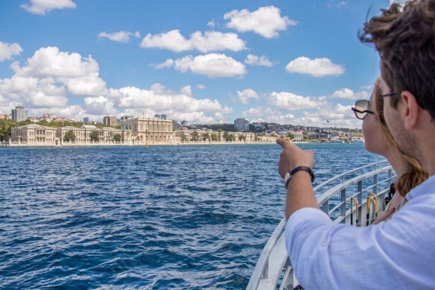 Eine Person deutet auf eine Küstenstadtlandschaft mit Gebäuden und wolkenlosem Himmel. 3