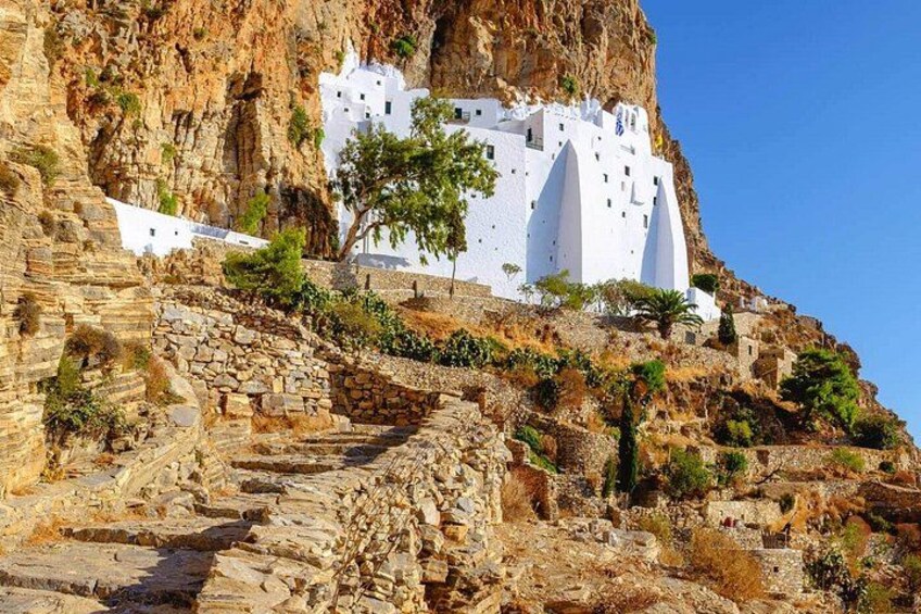 A white building on a rocky hillside with stone steps leading up to it. 1