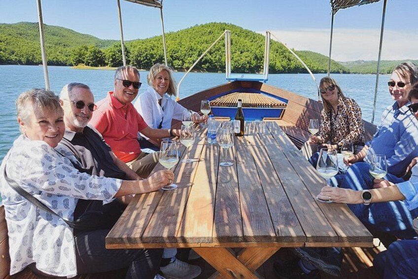 A group of people on a boat with a wooden table, surrounded by water and greenery. 3