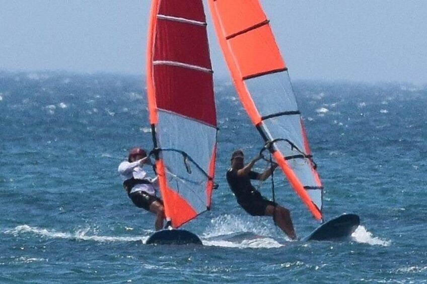 Zwei Personen windsurfen mit roten Segeln auf dem Meer. 4