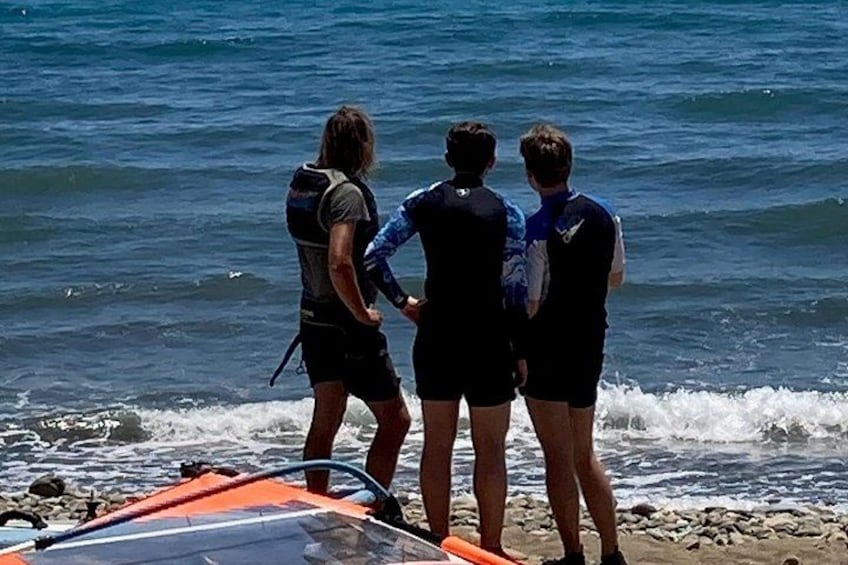 Drei Personen stehen auf einem felsigen Strand und blicken aufs Meer. 2