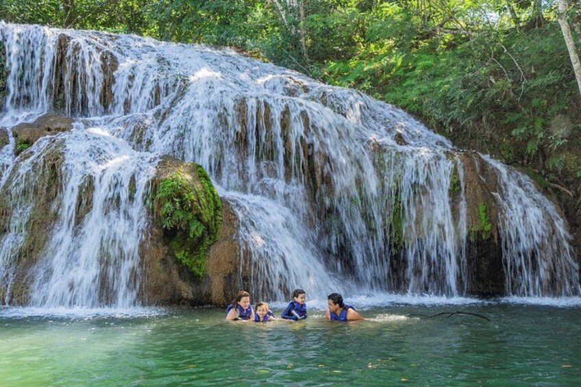 A waterfall with people swimming in the water below. 2