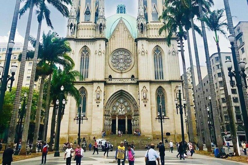 Une cathédrale à l’architecture gothique, entourée de palmiers et de bâtiments modernes. 1