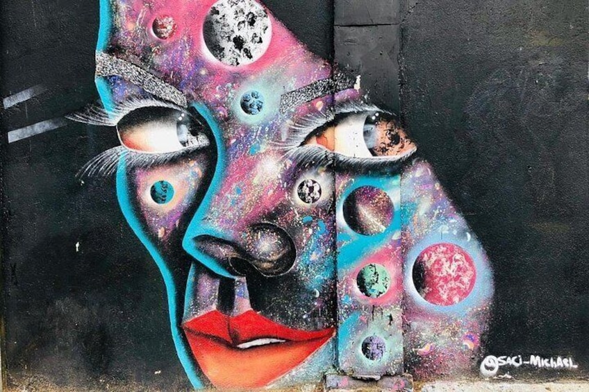 A graffiti mural with abstract human faces and celestial bodies. 3